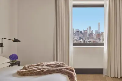 a bedroom with a window with a view of a city at The New York EDITION in New York