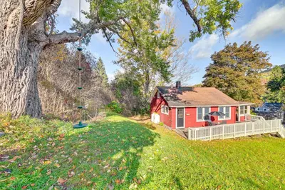 a red house in a field with a tree at Pet-Friendly Catskills Retreat Fire Pit and Deck! in Grand Gorge