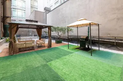 a patio with two umbrellas and green grass at Modern 3Bd Rose Hills Manhattan Terrace Space in New York