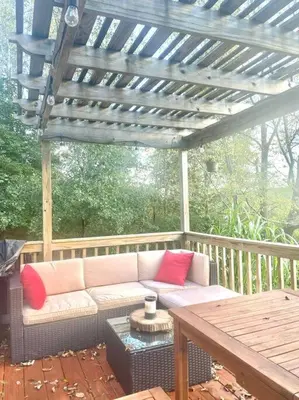 a couch sitting under a pergola on a patio at Corner's Cabin - A-Frame - Catskills NY in South New Berlin
