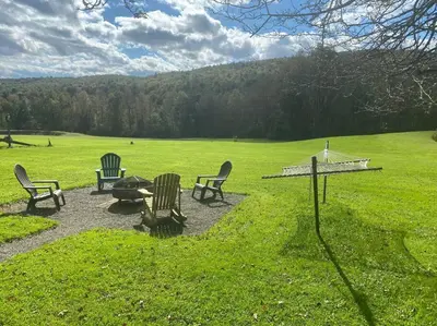 a group of chairs sitting in a grass field at Corner's Cabin - A-Frame - Catskills NY in South New Berlin