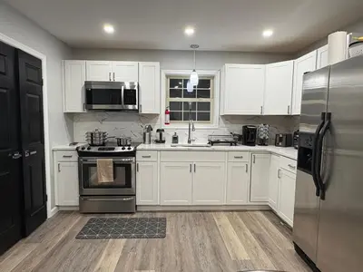 a kitchen with white cabinets and a stainless steel refrigerator at Cabin near kalahari,camelback Ski in Long Pond