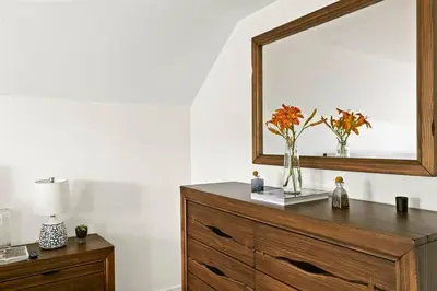 a dresser with a mirror and a vase with flowers on it at Classic Country 6 Bedroom in Kingston