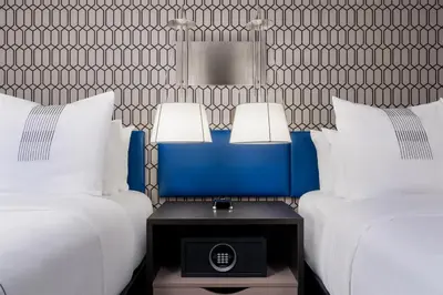 two beds with white pillows and a table with two lamps at GLō Best Western Bronx NYC in Bronx