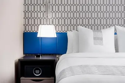 a bed with a blue headboard and a lamp on a table at GLō Best Western Bronx NYC in Bronx