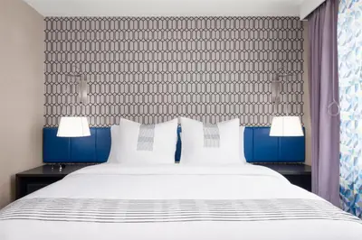 a bedroom with a large white bed with blue accents at GLō Best Western Bronx NYC in Bronx