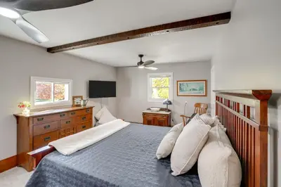 a bedroom with a bed and a dresser and windows at 1 Mi to Dtwn Cottage with Large Yard in Stockbridge in Stockbridge