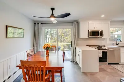 a kitchen and dining room with a table with flowers at 1 Mi to Dtwn Cottage with Large Yard in Stockbridge in Stockbridge