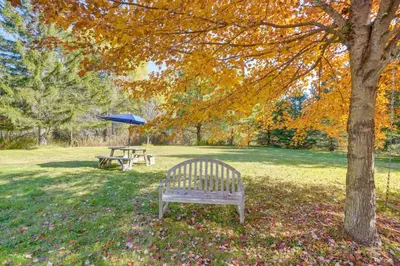 a park with a bench and a table with an umbrella at 1 Mi to Dtwn Cottage with Large Yard in Stockbridge in Stockbridge