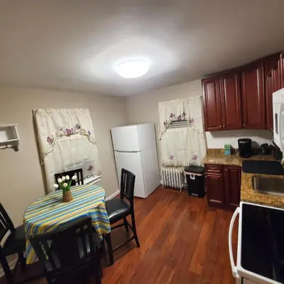 a small kitchen with a table and a refrigerator at Adorable 2 Bedrooms in Bellerose NY in Bellerose