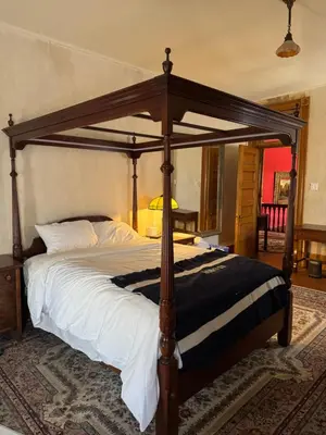 a bed with a wooden canopy in a bedroom at Haslett House - A Gilded Age Estate in Fort Plain