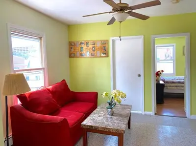a living room with a red couch and a ceiling fan at 3-bedrooms Journal Square near NYC in Jersey City