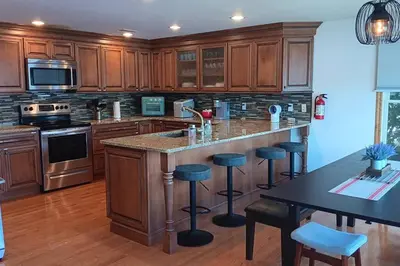 a kitchen with wooden cabinets and a island with bar stools at Falcon's Nest, Lakefront at Byram Cove, Hopatcong in Andover