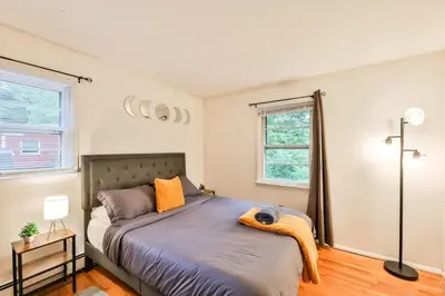 a bedroom with a bed with an orange blanket on it at Hunter Hideaway with Hot Tub in Lanesville