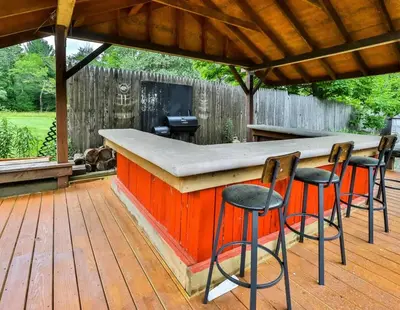 a bar on a deck with four stools at Hunter Hideaway with Hot Tub in Lanesville