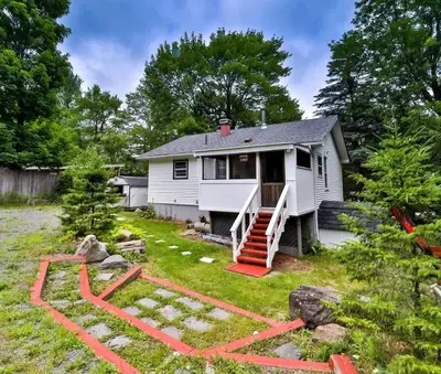 a small white house with a yard with red landscaping at Hunter Hideaway with Hot Tub in Lanesville