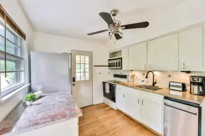 a kitchen with white cabinets and a ceiling fan at Hunter Hideaway with Hot Tub in Lanesville