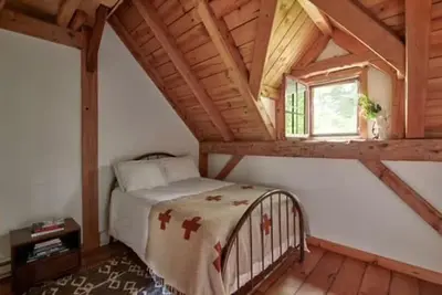 a bedroom with a bed and a window in a attic at Private Woodland Retreat with Cedar Hot Tub & Mt View in Gilboa