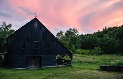 an old barn with a cross on the roof at sunset at Private Woodland Retreat with Cedar Hot Tub & Mt View in Gilboa