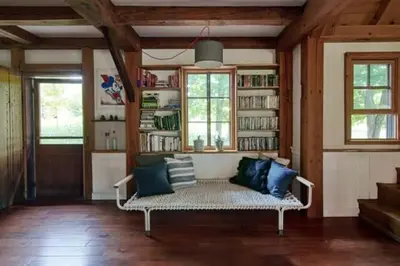 a living room with a couch and a book shelf at Private Woodland Retreat with Cedar Hot Tub & Mt View in Gilboa