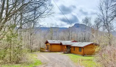 a wooden cabin in the middle of a forest at 4 Bedroom Log Cabin with Stream and Great Location in Lanesville