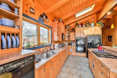 a large kitchen with wooden walls and wooden cabinets at 4 Bedroom Log Cabin with Stream and Great Location in Lanesville