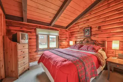 a bedroom with a bed and a tv in a log cabin at 4 Bedroom Log Cabin with Stream and Great Location in Lanesville