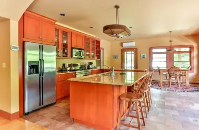 a kitchen with wooden cabinets and a stainless steel refrigerator at Country Escape Overlooking Hunter & Windham Mts in Jewett