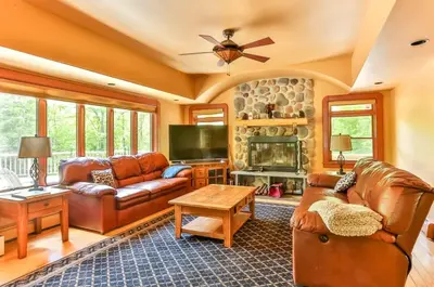 a living room with leather furniture and a stone fireplace at Country Escape Overlooking Hunter & Windham Mts in Jewett
