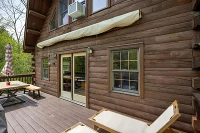 a wooden cabin with a picnic table on a deck at Cozy Athens Cabin on the Lake with Hot Tub & Backyard in Athens