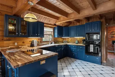 a kitchen with blue cabinets and a wooden ceiling at Cozy Athens Cabin on the Lake with Hot Tub & Backyard in Athens