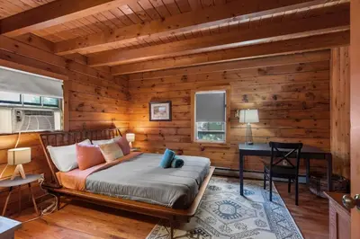 a log cabin bedroom with a bed and a desk at Cozy Athens Cabin on the Lake with Hot Tub & Backyard in Athens