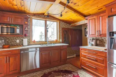 a kitchen with wooden cabinets and a large window at Cozy Rustic Bliss Seconds from Windham Mt Resort in Windham