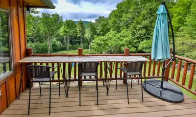 a table and chairs on a porch with an umbrella at Dog-Friendly Mountain Hideaway in Jewett