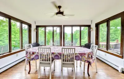 a dining room with a table and chairs and windows at Dog-Friendly Mountain Hideaway in Jewett