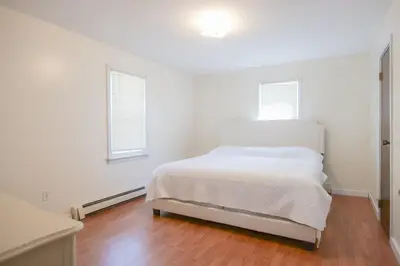 a white bedroom with a bed and two windows at High Falls Hideout in Catskill