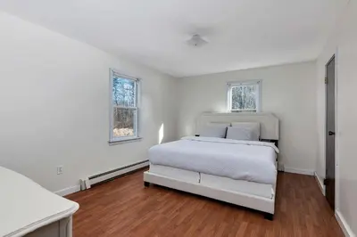 a white bedroom with a bed and two windows at High Falls Hideout in Catskill