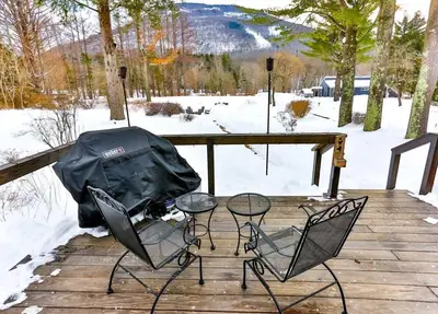 two chairs and a table on a deck in the snow at Majestic Mountain Retreat with Fire Pit Facing Mtn in Hunter