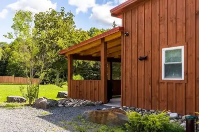 a wooden cabin with a large door in a yard at Mountain Cabin with Scenic Views and Hot Tub in Windham