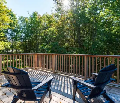 two chairs sitting on a deck with trees at Retro Retreat Charming Home with Hot Tub & Fire Pit in Hensonville