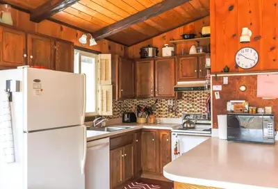 a kitchen with wooden cabinets and a white refrigerator at Retro Retreat Charming Home with Hot Tub & Fire Pit in Hensonville