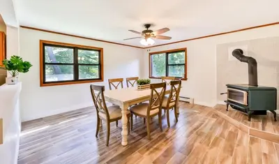 a dining room with a table and a wood stove at Stream-Side Atrium Home with Side Rooms & Pool Table in Hunter