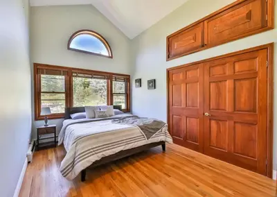 a bedroom with a bed and a wooden door at Stream-Side Atrium Home with Side Rooms & Pool Table in Hunter