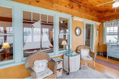 a living room with two chairs and a bed in a room at Lake Views and Dock Access - Pittsfield Cottage! in Pittsfield