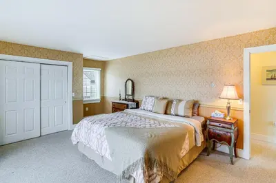 a bedroom with a bed and a table with a lamp at Lake Views and Dock Access - Pittsfield Cottage! in Pittsfield