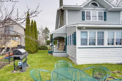 a yard with chairs and a grill in front of a house at Lake Views and Dock Access - Pittsfield Cottage! in Pittsfield