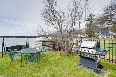 a grill and table with a table and chairs on the grass at Lake Views and Dock Access - Pittsfield Cottage! in Pittsfield