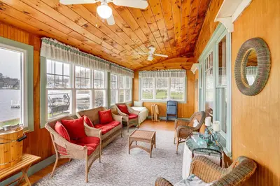 a living room with couches and chairs and windows at Lake Views and Dock Access - Pittsfield Cottage! in Pittsfield