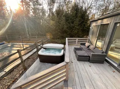 a deck with a hot tub and chairs on it at Luxury Woodstock Retreat Hot tub and heated pool in Woodstock