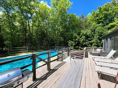 a wooden deck with a swimming pool and chairs at Luxury Woodstock Retreat Hot tub and heated pool in Woodstock